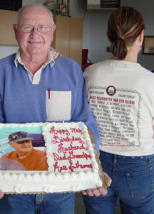 Special event photo of Bob holding cake with backside view of person wearing t-shirt